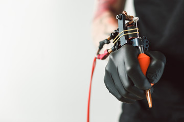 Tattoo artist holding tattoo machine on dark background with space for text