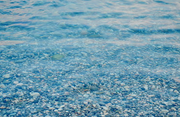 Texture of transparent crystal clear sea water and pebbles, summer sea water background