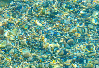 Fototapeta na wymiar Texture of transparent crystal clear sea water and pebbles, summer sea water background