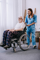 Obraz na płótnie Canvas Nurse pushing wheelchair with senior patient