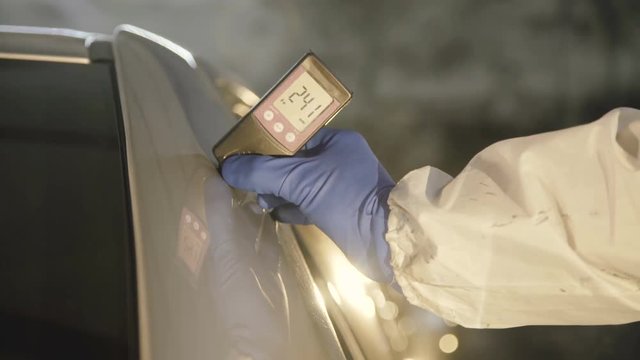 View of measuring a thickness of primer on a car surface using a thickness gauge