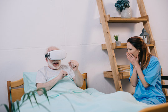 Nurse feeling excited about old man using vr glasses in bed