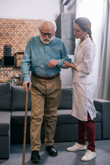 Female doctor standing by senior man with cane