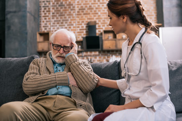 Female doctor supporting sad senior man