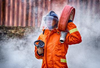 Obraz premium Emergency Fire Rescue training, firefighters in uniform, carry a water hose run through flame