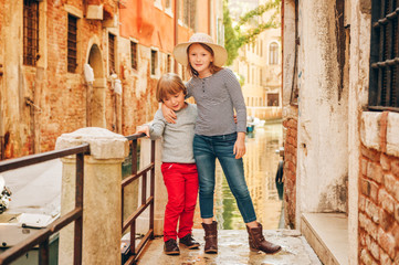 Obraz na płótnie Canvas Two kids playing on the bridge in Venice. Little girl and boy visiting Venice, Italy. Small tourists in Europe