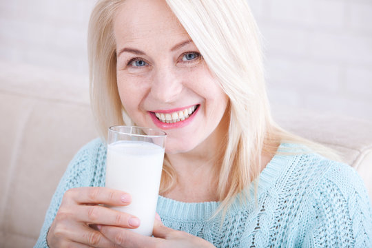 Happy middle aged woman drinking milk