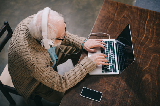 Top View Of Senior Man In Headphones Using Laptop
