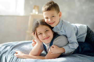 Two children, the boy and the girl, lie on a bed.