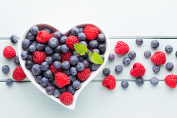 Juicy and fresh blueberries with green mint on rustic blue table.