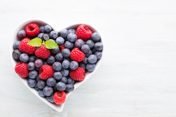 Juicy and fresh blueberries with green mint on rustic blue table.