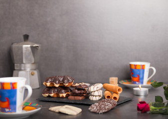 variety of biscuits on a table with coffee and flowers and candles