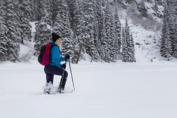 Adventurous girl snowshoeing in Joffre Lake, British Columbia, Canada.