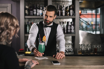 handsome bartender giving cocktail to girl