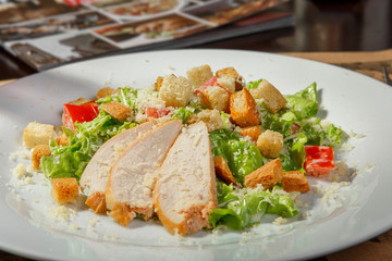 Caesar salad on a white plate, with chicken. Low key. Side view. Breakfast, lunch, dinner in the restaurant, cafe