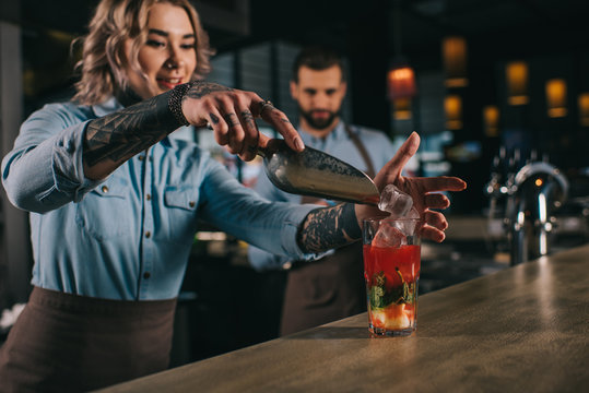 bartender adding ice into alcohol drink at bar