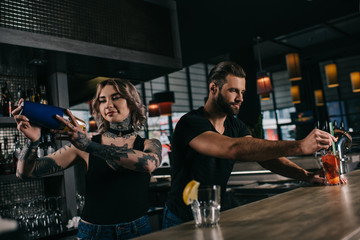 Obraz na płótnie Canvas young bartenders preparing alcohol drinks at bar