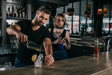 young bartenders preparing alcohol drinks at bar counter