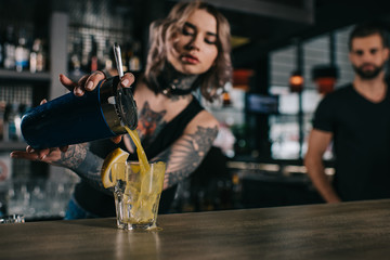 tattooed bartender preparing drink at bar - obrazy, fototapety, plakaty