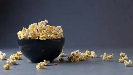 Popcorn in the bowl over grey background - obrazy, fototapety, plakaty
