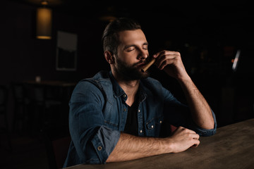 visitor sitting at bar counter and sniffing cigar