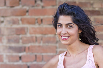 Portrait of Beautiful Happy Young  Woman with Curly Hair on a Brick Background