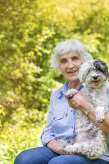Beautiful Happy Senior Woman Hugging her Cute Dog Outdoor