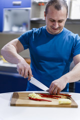 man cuts vegetables on a wooden lumber in the kitchen