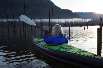 Adventurous woman kayaking during a beautiful morning. Taken in Stave Lake, East of Vancouver, British Columbia, Canada. Concept: Adventure, Travel, Holiday

