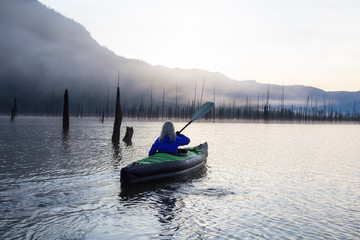 Adventurous woman kayaking during a beautiful morning. Taken in Stave Lake, East of Vancouver, British Columbia, Canada. Concept: Adventure, Travel, Holiday
