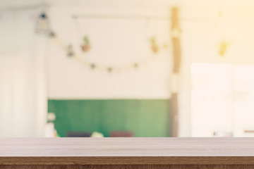 Empty wooden table top with blurred modern coffee shop background for product display and montage.