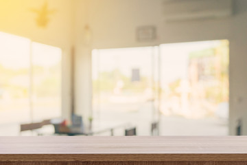 Empty wooden table top with blurred modern coffee shop background for product display and montage.