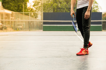 Badminton player in sport outfit is warm up before playing the game at outdoor hard court background