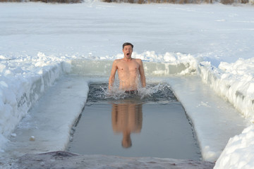 мужчина зимой ныряет под лёд