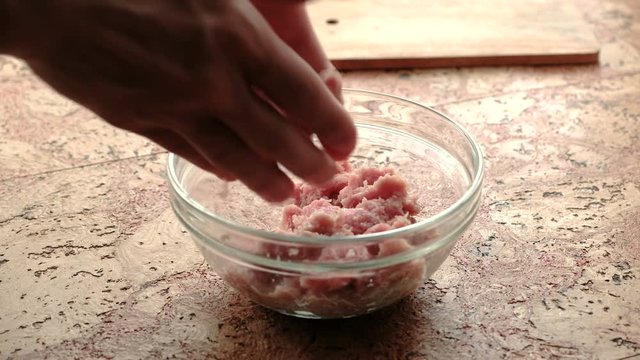 Close-up of man's hands make cutlets of minced meat. Transparent plate on the kitchen table.