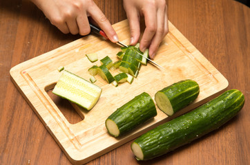 Slicing cucumber with a knife on the board
