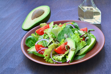 Green tossed salad with  leafy vegetables, arugula, baby spinach, avocado, cherry tomatoes and pumpkin seeds.