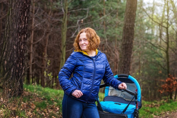 Mother with baby stroller for a walk in the woods.