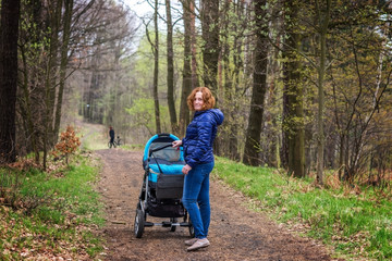 Mother with baby stroller for a walk in the woods.