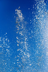 Splashing water from a fountain against the blue sky