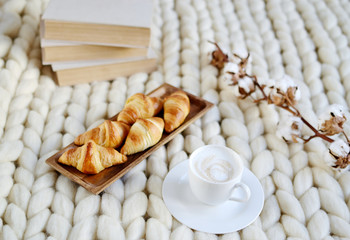 Cup with cappuccino and croissants, white pastel giant blanket, bedroom, flower cotton, spring, woman day, morning concept 