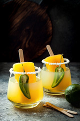 Spicy mango popsicle margarita cocktail with jalapeno and lime. Mexican alcoholic drink for Cinco de mayo party