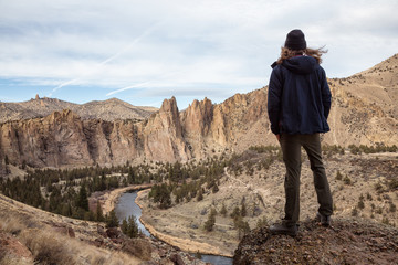 Naklejka premium Man enjoying the Beautiful American Mountain Landscape during a vibrant winter day. Taken in Smith Rock, Redmond, Oregon, America. Concept: Adventure, Holiday and Travel