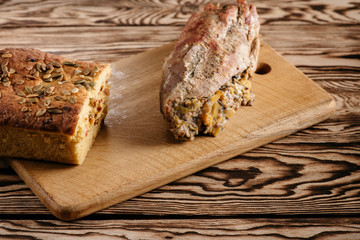Pumpkin muffin and baked meat roll with a wooden stick on a black background