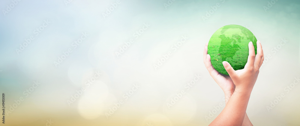 Wall mural earth day concept: child hands holding earth globe of grass over blurred green nature background