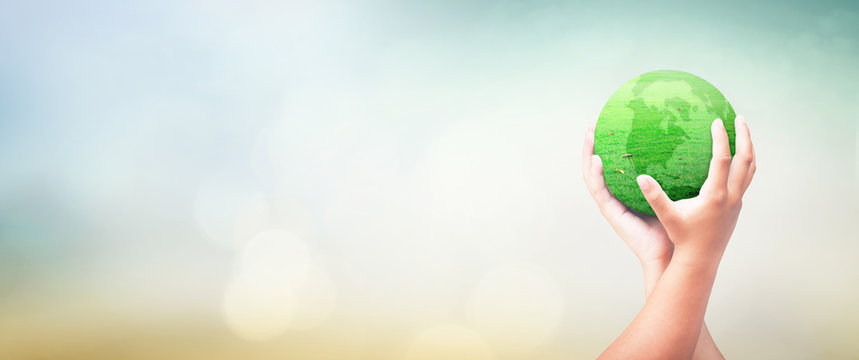 World environment day concept: Child hands holding earth globe of grass over blurred green nature background