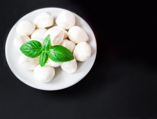 Fresh cherry tomatoes, basil leaf, mozzarella cheese on black slate stone chalkboard with copyspace. Healthy Italian traditional caprese salad ingredients. Organic Mediterranean food concept, flat lay
