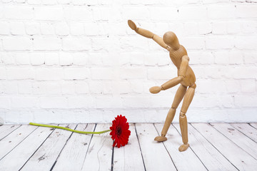 Wooden mannequin with red gerbera flower