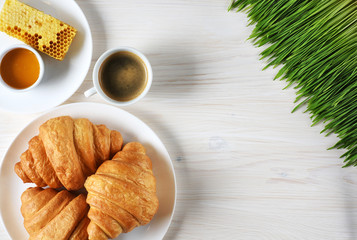 Croissants, coffee, honey and sprouted wheat on a wooden background. Breakfast flat lay.