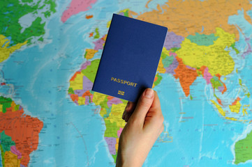 blue passport on the world map in women's hands